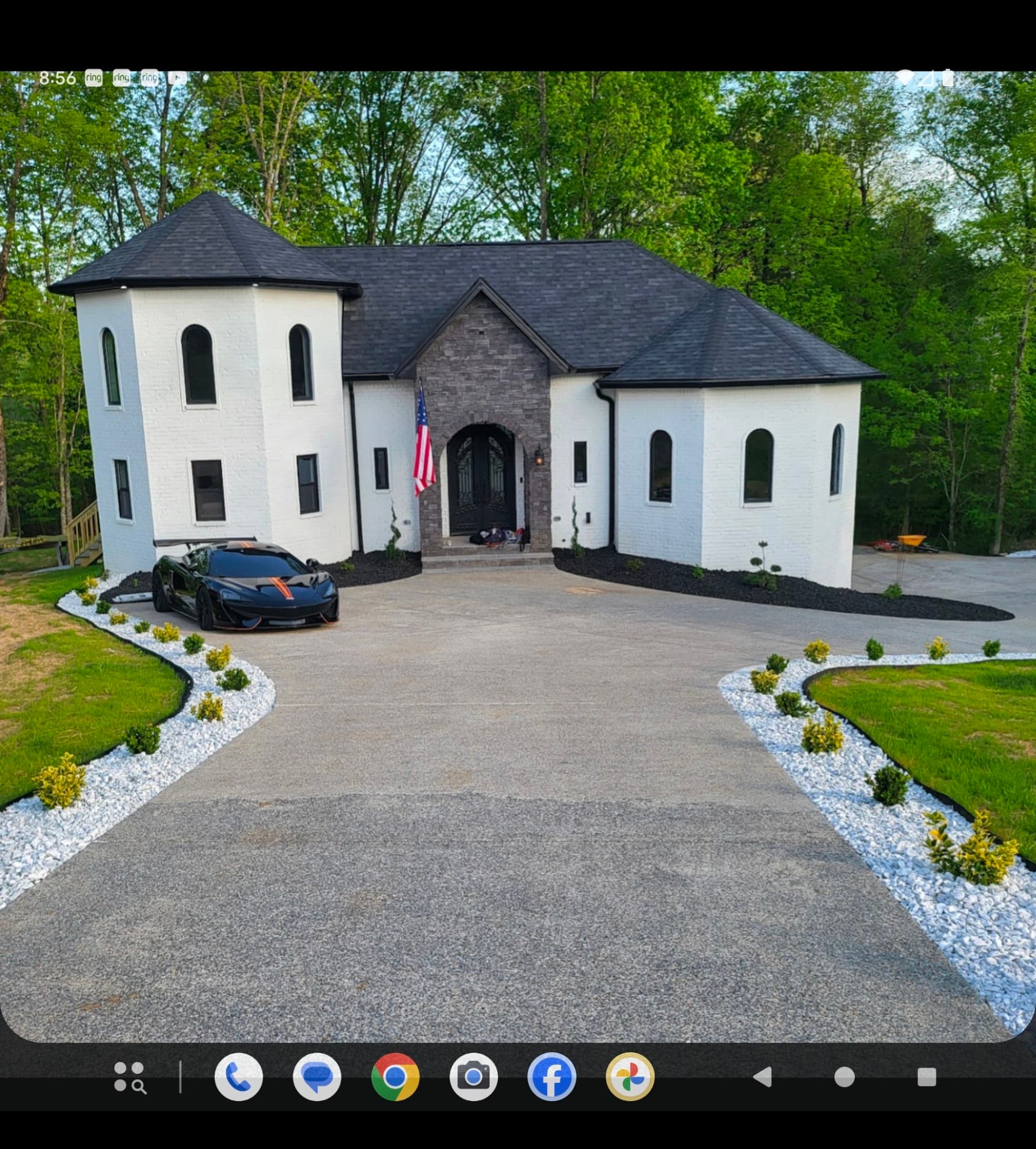 Modern white brick house with black roof and a black sports car in the driveway.