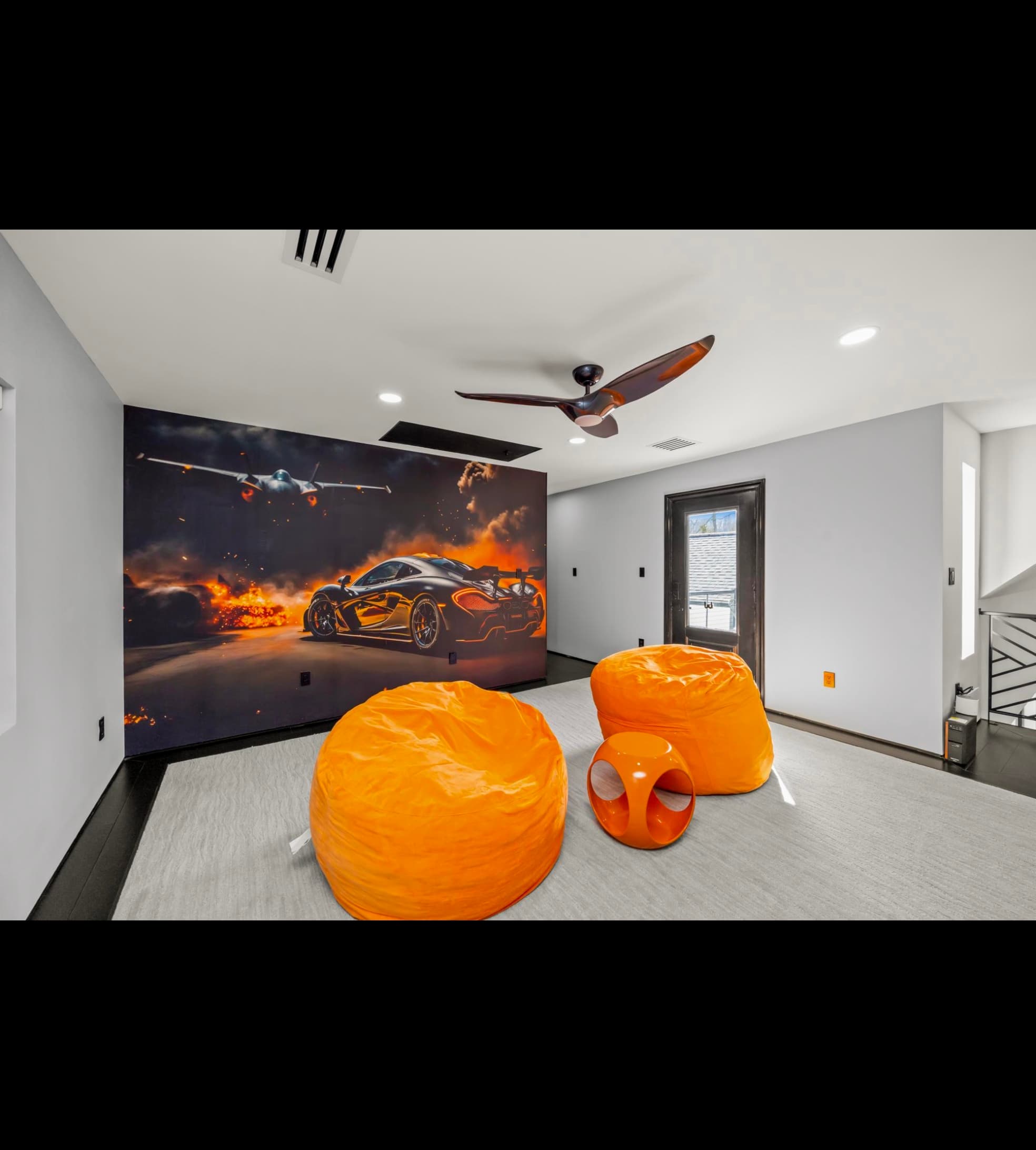 Modern room featuring a fiery sports car mural, two orange beanbag chairs, and gray carpet.