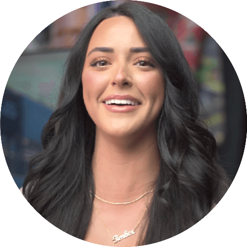 Smiling woman with long wavy dark hair and gold necklaces in a circular frame.